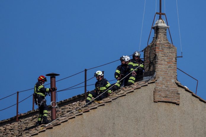 Members of the fire and rescue service set a chimney on the roof of the Sistine Chapel, ahead of the conclave, at the Vatican